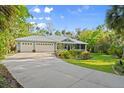 Inviting home boasts a three-car garage and screened porch, set amidst lush landscaping and mature trees at 2030 Waterford Estates Dr, New Smyrna Beach, FL 32168