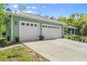 Large three-car garage shows white doors, metal roof, and landscaping, creating great curb appeal at 2030 Waterford Estates Dr, New Smyrna Beach, FL 32168