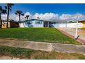 Inviting home featuring a well-maintained lawn, beautiful blue exterior, and palm trees at 2573 W Coral Way, Daytona Beach, FL 32118