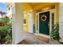 Inviting green front door with a wreath, decorative 'HOME' sign, and a brick-paved porch at 2982 S Atlantic Ave, New Smyrna Beach, FL 32169