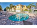 Stunning community pool with brick surround, white fence, and palm trees behind yellow condo building at 2982 S Atlantic Ave, New Smyrna Beach, FL 32169