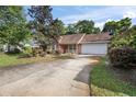 Attractive single-story home with a brick facade, attached garage, and a long driveway at 405 Secluded Oaks Trl, Deland, FL 32724