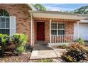 Welcoming front porch with a red brick facade and red front door and white trim at 405 Secluded Oaks Trl, Deland, FL 32724