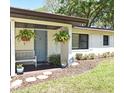 Close-up of a charming front porch with a blue door, hanging plants, and a cozy bench at 421 Hope Ter, Maitland, FL 32751