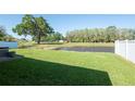 Lush green backyard with pond view, partial fencing and mature tree, creating a private and serene outdoor space at 5479 Saint Regis Way, Port Orange, FL 32128