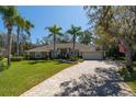 Inviting home featuring a lush green lawn, palm trees, and a circular brick driveway at 6194 Half Moon Dr, Port Orange, FL 32127
