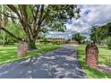 Long driveway leading to a beautiful home, framed by brick pillars and mature trees at 910 N Kepler Rd, Deland, FL 32724