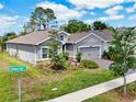 Beautifully landscaped home with a gray exterior, green lawn and view of Chelan Falls Dr at 1002 Chelan Falls Dr, Deland, FL 32724