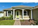 Inviting front porch with white columns and a vibrant green door, offering a warm welcome at 1613 Lady Fern Trl, Deland, FL 32720