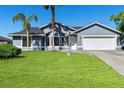 Charming light blue home with a well-manicured lawn, complemented by palm trees and a two-car garage at 1842 W Cooper Dr, Deltona, FL 32725