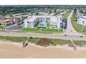 Aerial view of a condo complex on a green lawn near a sandy beach and ocean at 1926 Ocean Shore Blvd # 3050, Ormond Beach, FL 32176