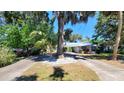 This single-story home features a metal roof, a circular driveway, and a front yard with mature trees at 1927 Orange Tree Dr, Edgewater, FL 32141