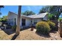 Home's rear view featuring large windows, established shrubbery, and partial view of a fenced yard at 1927 Orange Tree Dr, Edgewater, FL 32141