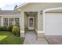 Covered front entryway with beautiful landscaping and a white door with glass inset panels at 227 Heronwood Cir, Deltona, FL 32725