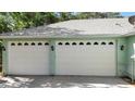 Spacious three-car garage with white doors, decorative windows, and exterior lighting, offering ample parking and storage at 2635 Wood Duck Vlg, Deland, FL 32720