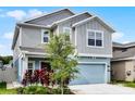 Stylish two-story home with an inviting blue garage door, beautiful plants, and well-maintained landscaping at 2743 Gentle Rain Dr, Davenport, FL 33837