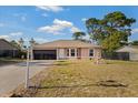 Inviting single-story home featuring a two-car garage, manicured lawn, and charming decorative fountain at 3109 Sky St, Deltona, FL 32738