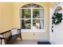 Inviting front porch with a bench, decorative window, and a white door adorned with a beautiful wreath at 3140 Kailani Ct, Ormond Beach, FL 32174