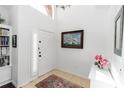 Bright foyer featuring tile flooring, fresh white paint, a nautical painting, and a decorative rug at 320 Conch Key Way, Sanford, FL 32771
