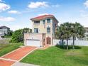 Beautiful three-story home with a red tile roof, well-manicured lawn, and palm trees at 3817 Islamorada Dr, Ormond Beach, FL 32176