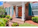A welcoming orange front door with seasonal wreath is surrounded by white columns and manicured landscaping at 4 Huntsman Look, Ormond Beach, FL 32174