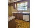 Outdated kitchen with wood cabinets, double sink, a window and a dishwasher at 461 Marigold Rd, Casselberry, FL 32707