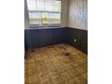 An interior room with faux brick and wood paneling, a window, and damaged floor at 461 Marigold Rd, Casselberry, FL 32707