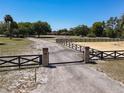 View of a gated entrance to the property with a long driveway leading to the house and arena at 685 Enterprise Osteen Rd, Osteen, FL 32764