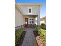 Inviting front porch with table and seating, brick pavers, stone accents, mature landscaping, and a red door at 1374 Red Clover Ln, Deland, FL 32724