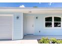 Close up of a light blue home's front door, with a white garage door and an arched window at 1598 Montgomery Ave, Daytona Beach, FL 32117