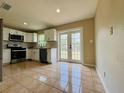 Bright kitchen with white cabinets, stainless steel appliances, tiled floors, and access to the backyard through double doors at 1808 Green Pl, Ormond Beach, FL 32174