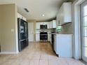 Modern kitchen featuring stainless steel appliances, white cabinets, and tiled floors for a stylish and functional cooking space at 1808 Green Pl, Ormond Beach, FL 32174