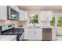 Modern kitchen featuring white cabinets, stainless steel appliances, and a view of the backyard at 1808 Green Pl, Ormond Beach, FL 32174