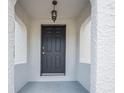 Close-up view of a classic black front door with textured white pillars and a vintage pendant light above at 216 Earl St, Daytona Beach, FL 32118