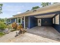 Carport of a blue home, with a concrete floor, white lattices, and a white door on the side at 220 Buena Vista St, Debary, FL 32713