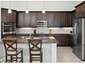 Modern kitchen features stainless steel appliances, dark wood cabinets, granite countertops, and an island with bar seating at 225 Mosaic Blvd, Daytona Beach, FL 32124