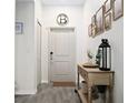 Hallway entrance features gray wood-like floors, a light-colored console table, and art frames on the wall at 2518 Hoptree Ln, Edgewater, FL 32141