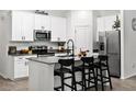 Modern kitchen featuring white cabinets, a kitchen island with seating, stainless steel appliances, and dark countertops at 2518 Hoptree Ln, Edgewater, FL 32141