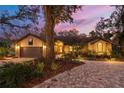 Charming home with lush landscaping, brick driveway, and warm exterior lighting at 2628 Spruce Creek Blvd, Port Orange, FL 32128