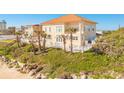 Beautiful home nestled on a grassy hill with palm trees and a white picket fence near the beach at 33 Ocean Shore Blvd, Ormond Beach, FL 32176