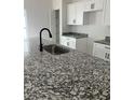 Stylish kitchen featuring granite countertops, stainless steel sink, modern fixtures, and white cabinetry at 516 Model St, Daytona Beach, FL 32114