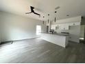 Open-concept living room with gray floors, modern lighting, and a kitchen island with granite countertops at 516 Model St, Daytona Beach, FL 32114