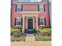 Charming two-story townhome featuring a bright pink facade, black shutters, and manicured landscaping at 103 Manor View Ln, Deland, FL 32724