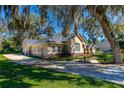 Stunning exterior view of the home with a long driveway, mature trees, and lush landscaping at 1309 Wicklow Ln, Ormond Beach, FL 32174