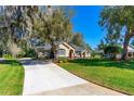 Beautiful home exterior with a well-manicured lawn, mature trees, and a long driveway at 1309 Wicklow Ln, Ormond Beach, FL 32174