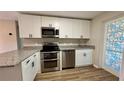 Modern kitchen featuring stainless steel appliances, granite countertops, white cabinets, and stylish door at 175 Center St, Daytona Beach, FL 32117