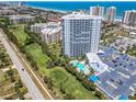 Aerial view features the high-rise condo building next to a lush golf course and ocean at 2 Oceans West Blvd # 1007, Daytona Beach, FL 32118
