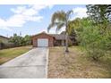 Charming brick home featuring a one-car garage, concrete driveway, and tropical landscaping at 2126 Sabal Palm Dr, Edgewater, FL 32141