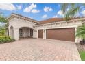 Exterior with a brick driveway and a two-car garage, showcasing the home's architectural details at 2811 S Asciano Ct, New Smyrna Beach, FL 32168