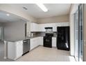 Modern kitchen with white cabinets, stainless steel dishwasher, granite countertops and black appliances at 417 Victoria Hills Dr, Deland, FL 32724